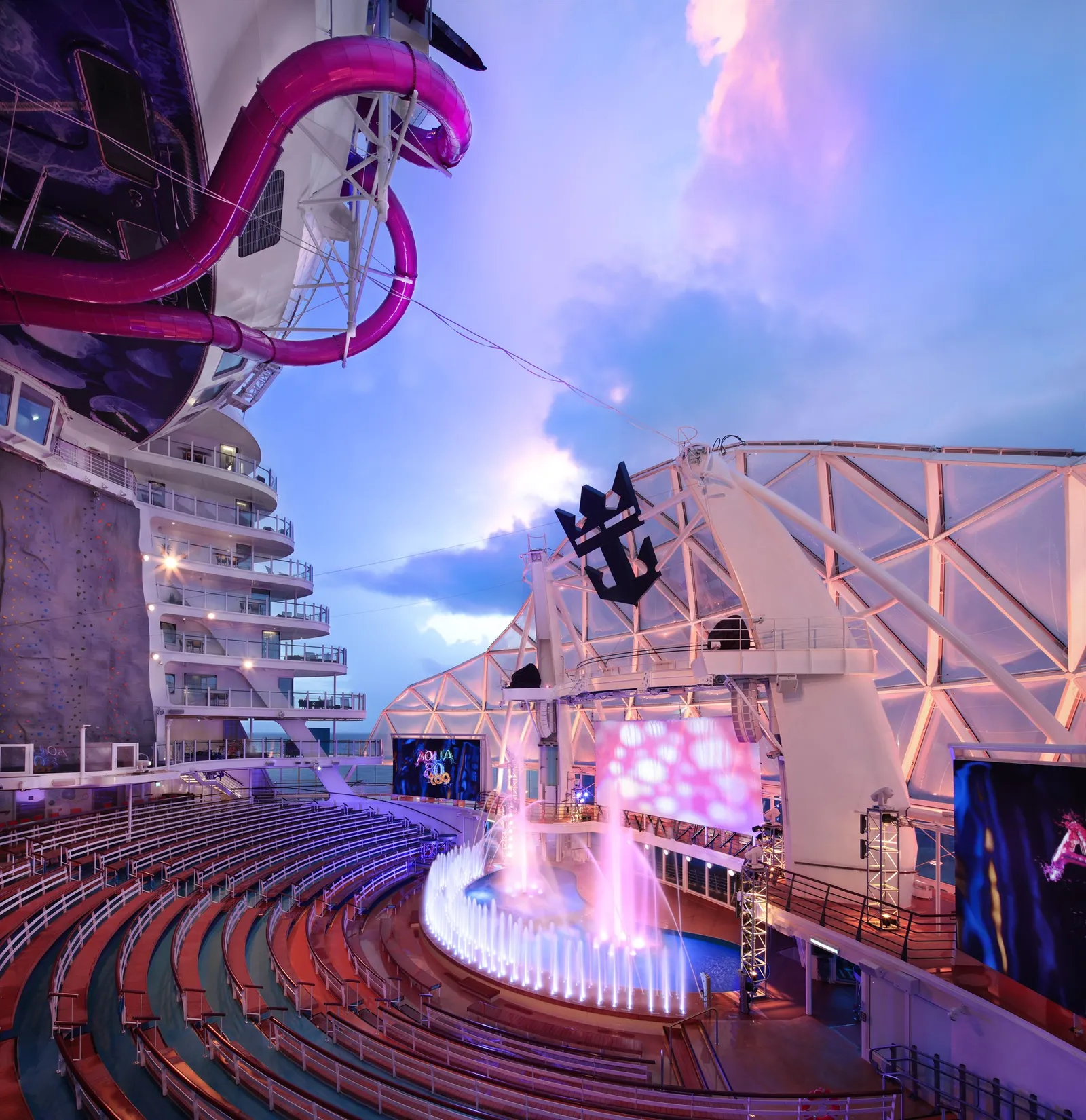 The AquaTheater on Utopia of the Seas lit up at dusk